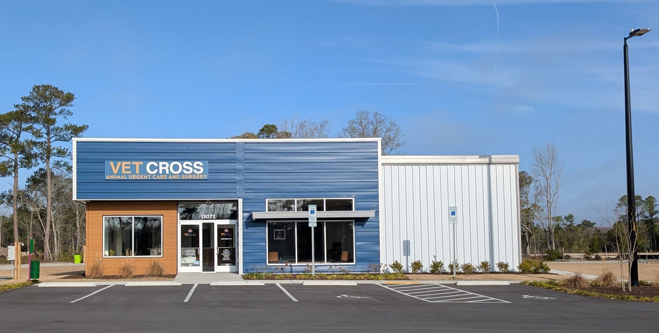 Vet Cross Office as seen from the parking lot, Blue and white building with light orange/brown accents and large sign that reads Vet Cross Animal Urgent Care and Surgery