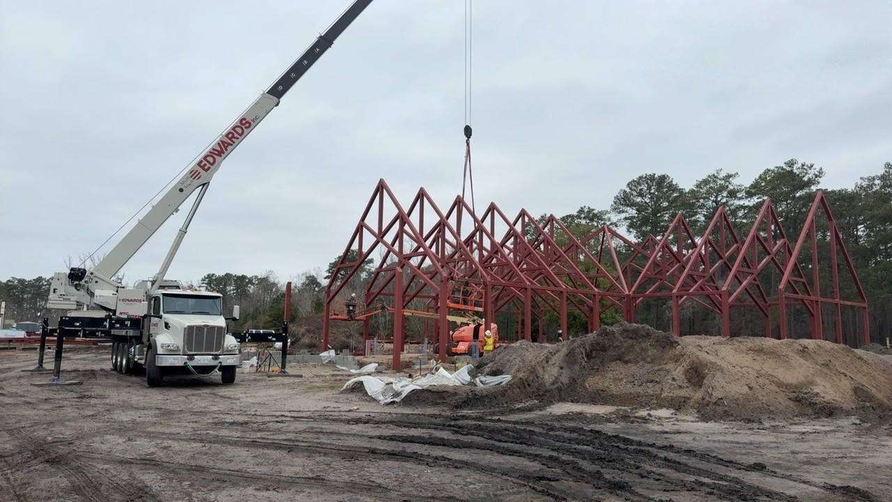 Red metal frame of a chapel with a construction crane
